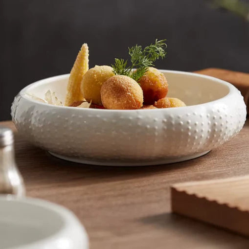 White textured bowl with fried appetizers on a wooden table
