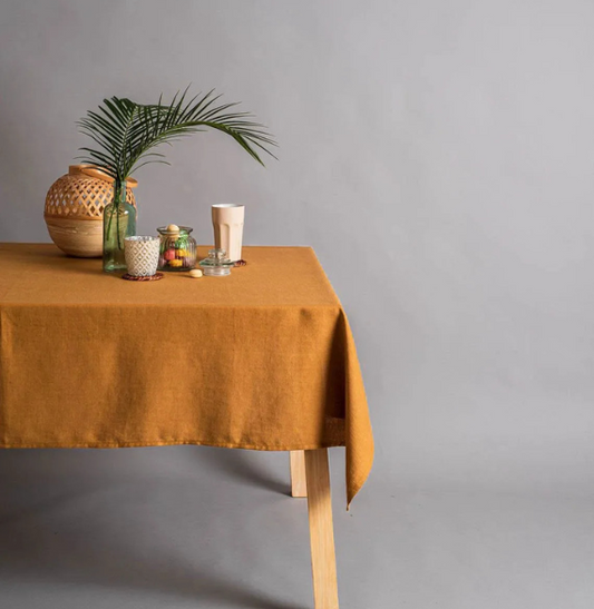 Table with a mustard yellow tablecloth against a gray background